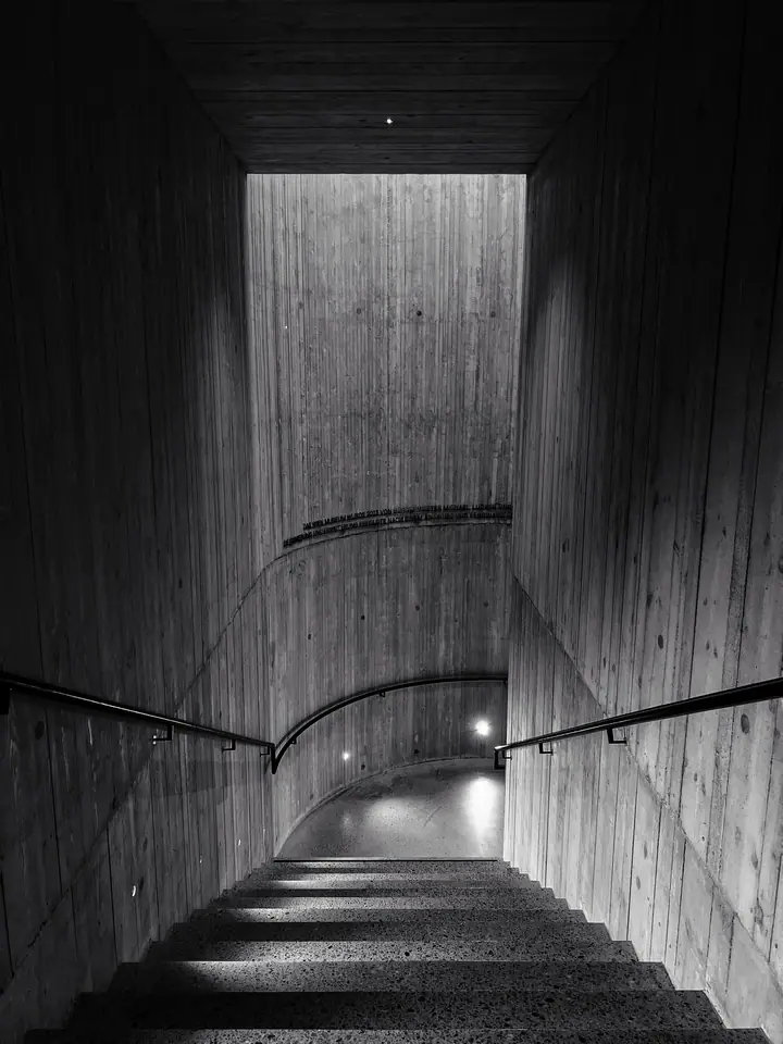 Monochrome concrete stairwell descending into shadow.